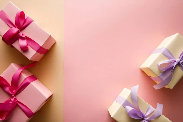 Top view of gift boxes with ribbons on pink and beige background — Stock Photo