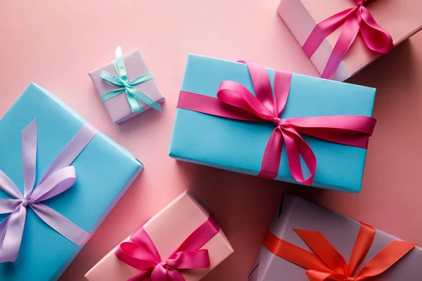 Blick von oben auf bunte Geschenkboxen mit Satinbändern auf rosa Hintergrund — Stockfoto