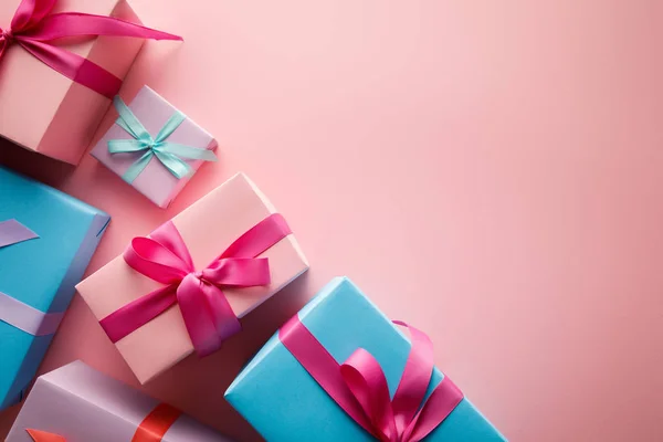 Blick von oben auf bunte Geschenkboxen mit Satinbändern auf rosa Hintergrund — Stockfoto