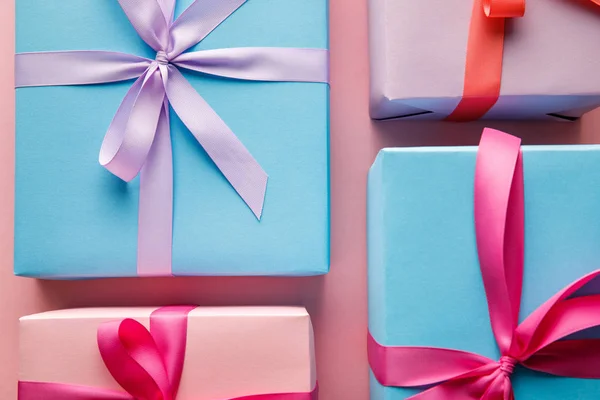 Top view of colorful gift boxes with ribbons on pink background — Stock Photo