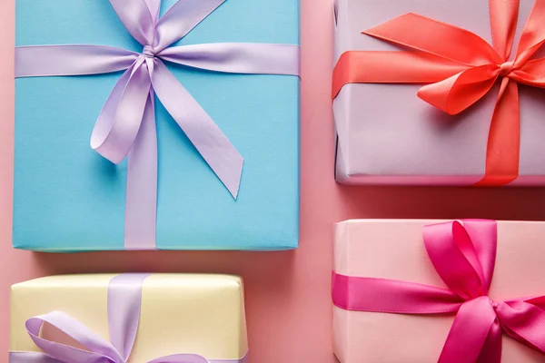 Top view of colorful gift boxes with ribbons on pink background — Stock Photo