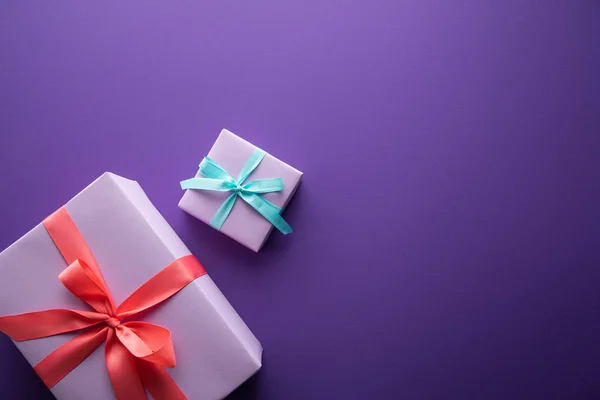 Vista superior de coloridas cajas de regalo con cintas y arcos sobre fondo púrpura con espacio para copiar — Stock Photo