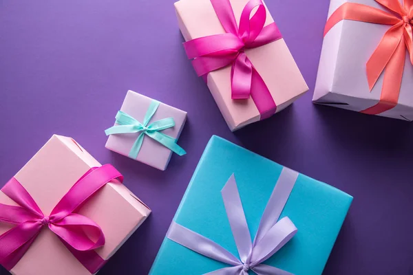 Vista superior de coloridas cajas de regalo con cintas y arcos sobre fondo púrpura — Stock Photo