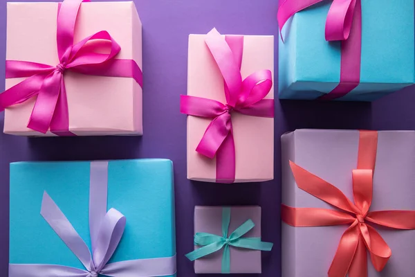 Вид сверху на красочные подарочные коробки с лентами и бантами на фиолетовом фоне — стоковое фото