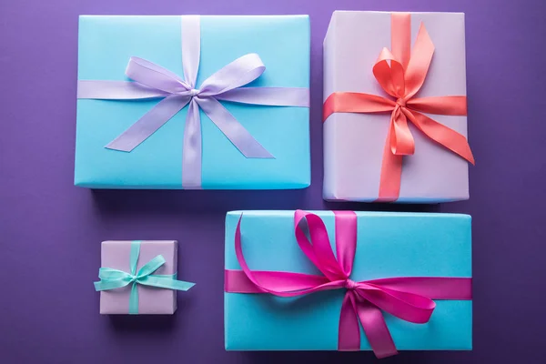 Top view of colorful gift boxes with ribbons and bows on purple background — Stock Photo