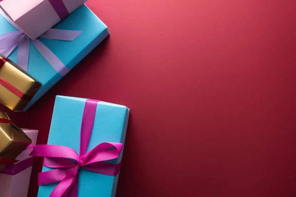 Top view of colorful gift boxes with ribbons on red background with copy space — Stock Photo