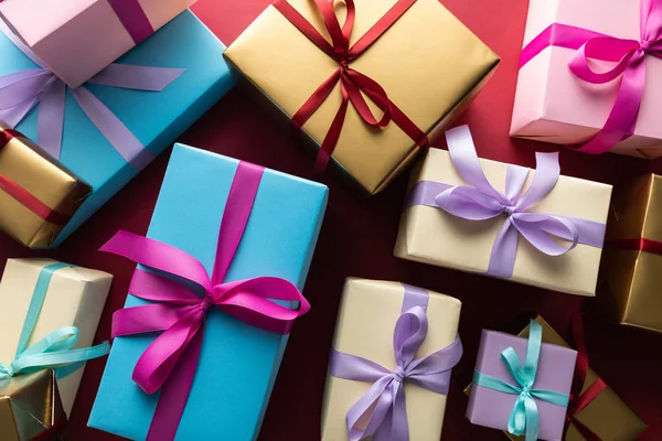 Draufsicht auf bunte Geschenkboxen mit Bändern auf rotem Hintergrund — Stockfoto