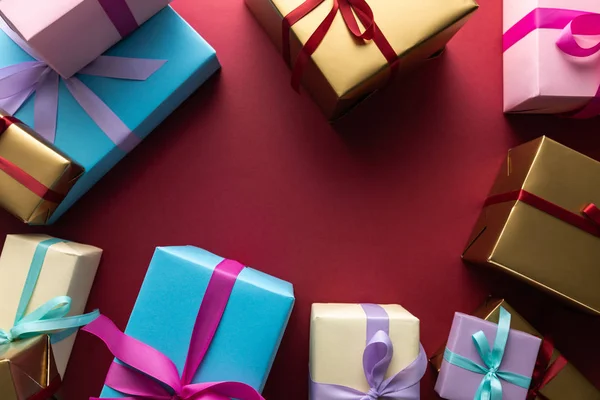 Top view of colorful gift boxes with ribbons on red background with copy space — Stock Photo