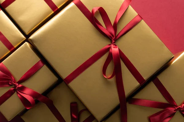 Top view of golden gift boxes with ribbons on red background — Stock Photo