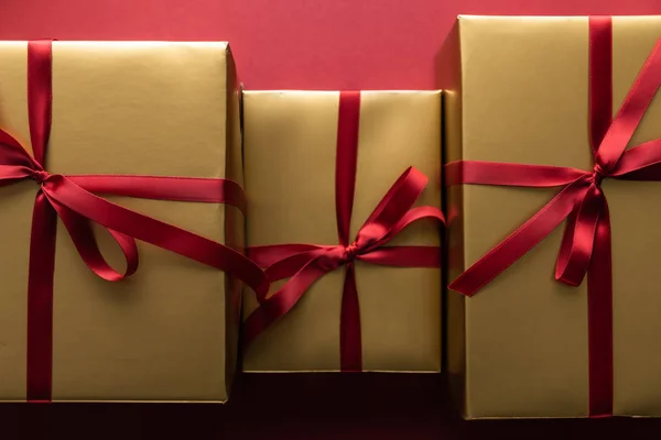 Flat lay with golden gift boxes with ribbons on red background — Stock Photo