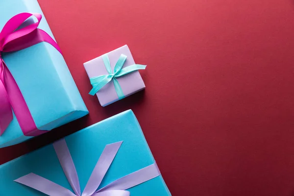 Vista superior de cajas de regalo azules y violetas con cintas sobre fondo rojo con espacio para copiar — Stock Photo