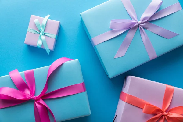 Draufsicht auf bunte Geschenkboxen mit Bändern auf blauem Hintergrund — Stockfoto