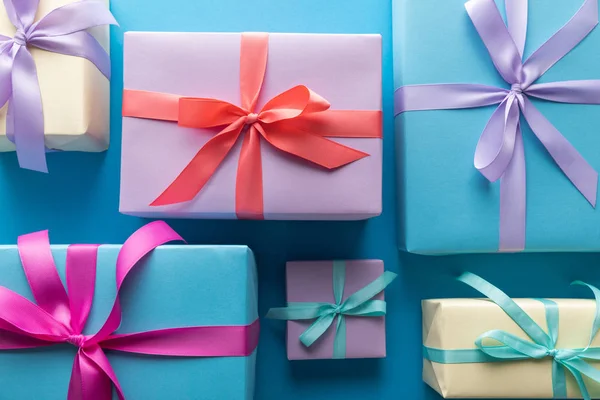 Flat lay with colorful gift boxes with ribbons on blue background — Stock Photo