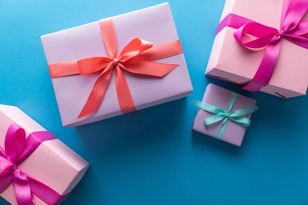 Draufsicht auf bunte Geschenkboxen mit Bändern auf blauem Hintergrund — Stockfoto
