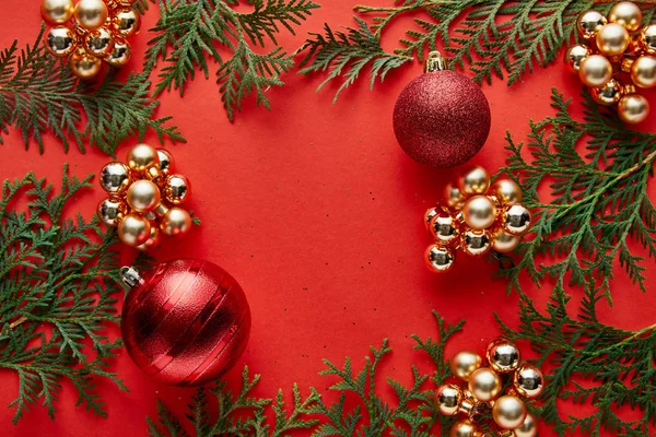 Vista superior de la brillante decoración de Navidad y thuja sobre fondo rojo con espacio para copiar - foto de stock
