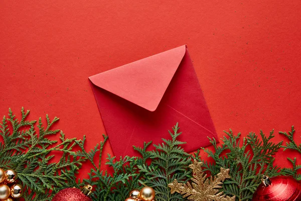 Top view of shiny Christmas decoration, envelope and thuja on red background with copy space — Stock Photo