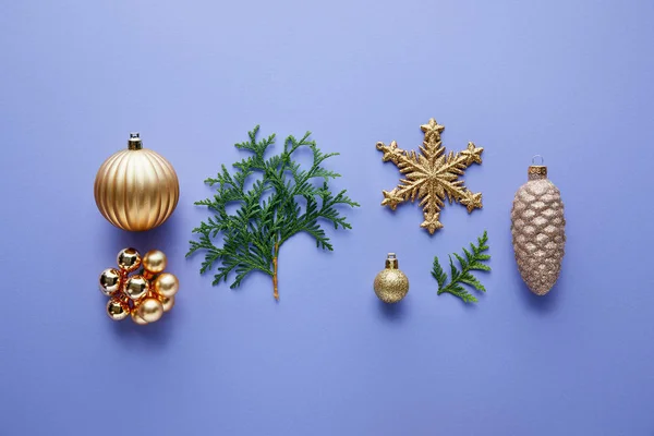 Top view of shiny golden Christmas decoration, green thuja branches on blue background — Stock Photo