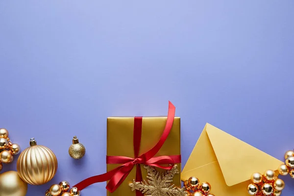 Top view of shiny golden Christmas decoration, envelope and gift box on blue background — Stock Photo