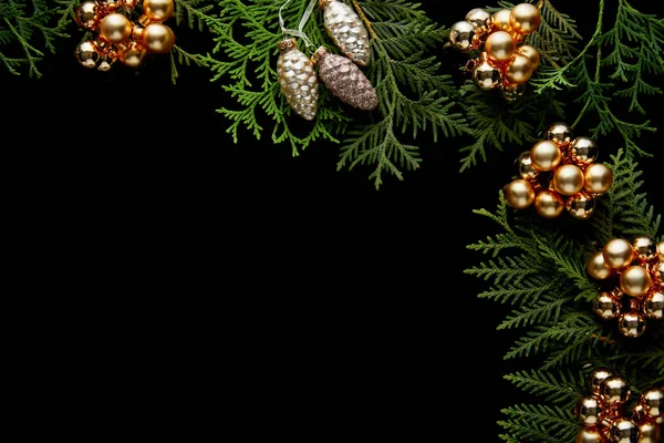 Top view of shiny golden Christmas decoration on green thuja branches isolated on black with copy space — Stock Photo