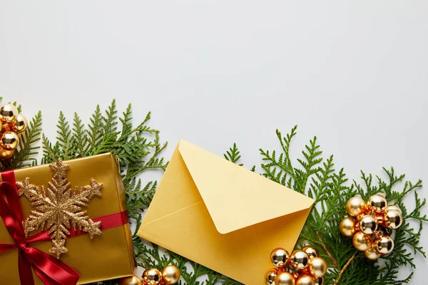 Vista superior da decoração dourada brilhante do Natal, presente e envelope em ramos thuja verdes isolados no branco — Fotografia de Stock