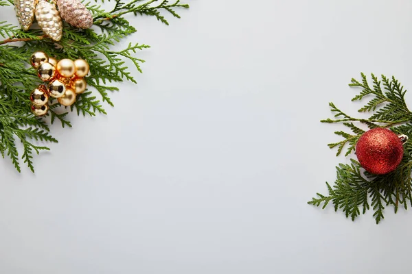 Верхний вид блестящего золотистого и красного рождественского украшения на зеленые ветви туи изолированы на белом с копировальным пространством — стоковое фото