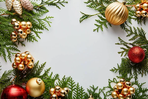 Marco de brillante decoración de Navidad dorada y roja en ramas de thuja verde aisladas en blanco con espacio de copia - foto de stock