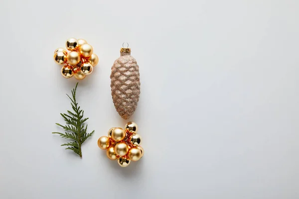 Piso con brillante decoración navideña dorada y rama de thuja verde aislada en blanco con espacio para copiar - foto de stock