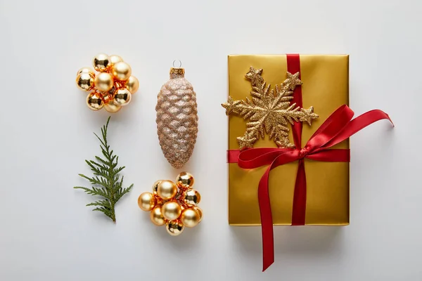 Plat couché avec une décoration de Noël dorée brillante, cadeau et branche thuja vert isolé sur blanc — Photo de stock