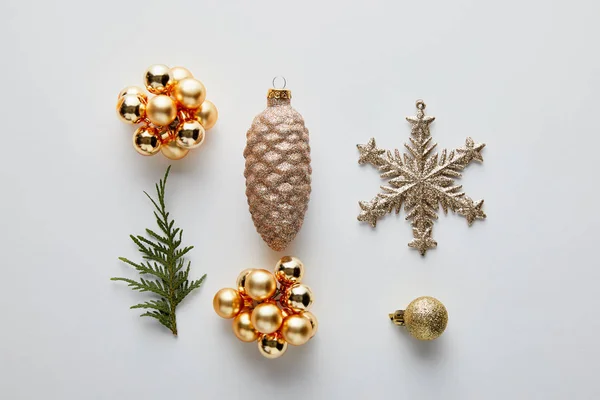 Flache Lage mit goldglänzendem Weihnachtsschmuck und grünem Thuja-Zweig isoliert auf weiß — Stockfoto
