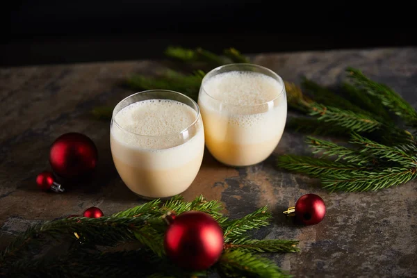 Delicioso coquetel de gemada, ramos de abeto e bolas de Natal na mesa de mármore escuro isolado em preto — Fotografia de Stock