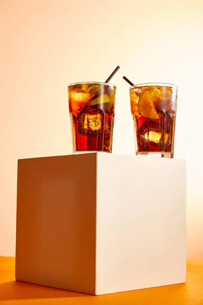 Vista ad angolo basso di cocktail cuba libre in bicchieri con cannucce sul cubo — Foto stock