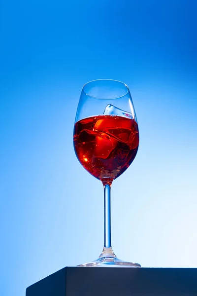 Low angle view of cocktail Aperol Spritz with ice cube in glass on blue background — Stock Photo