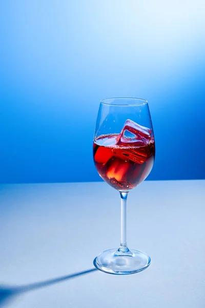 Cóctel Aperol Spritz con cubitos de hielo en vidrio sobre fondo azul - foto de stock