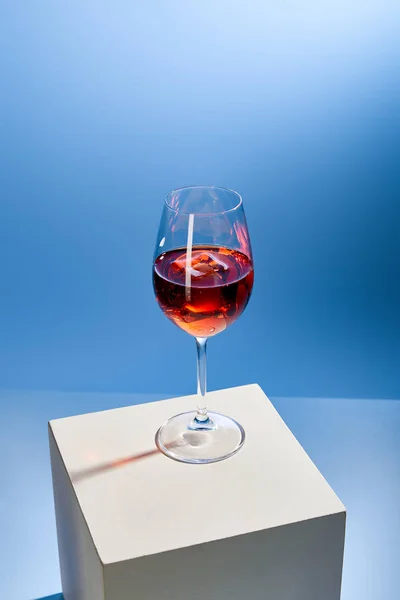 Коктейль Aperol Spritz с кубиком льда в стекле на синем фоне — стоковое фото