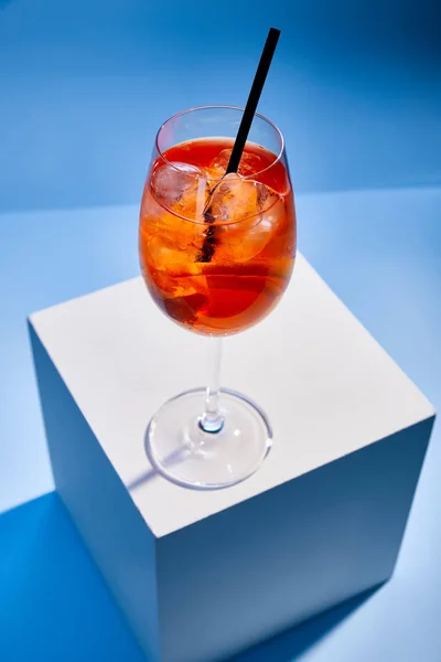 Vista de alto ângulo de cocktail Aperol Spritz com palha em vidro sobre fundo azul — Fotografia de Stock