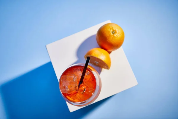 Top view of cocktail Aperol Spritz with straw in glass and oranges on blue background — Stock Photo