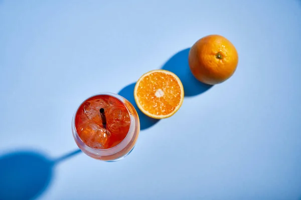 Vue du dessus du cocktail Aperol Spritz avec paille en verre et oranges sur fond bleu — Photo de stock