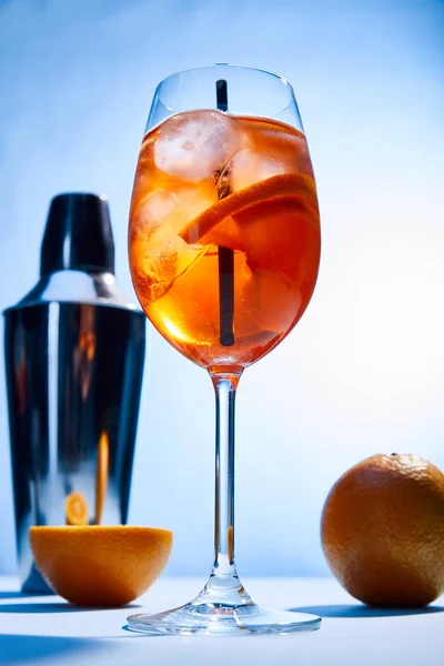 Vista ad angolo basso del cocktail Aperol Spritz, arance, shaker su sfondo blu — Foto stock