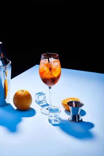 Cóctel Aperol Spritz, naranjas, coctelera, cubitos de hielo y taza de medir - foto de stock