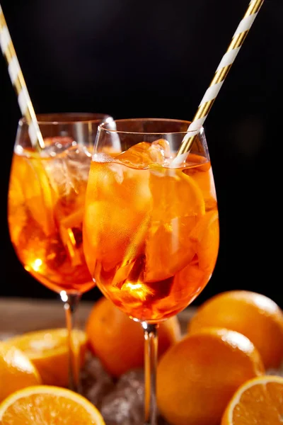 Aperol Spritz in Gläsern und Orangen auf schwarzem Hintergrund — Stockfoto
