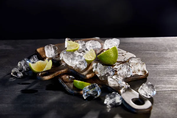 Ice cubes and cut limes on wooden cutting boards — Stock Photo