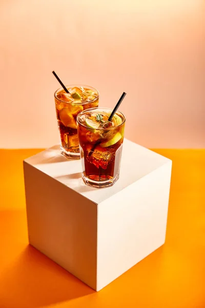 Cócteles cuba libre en vasos con pajitas sobre cubo - foto de stock