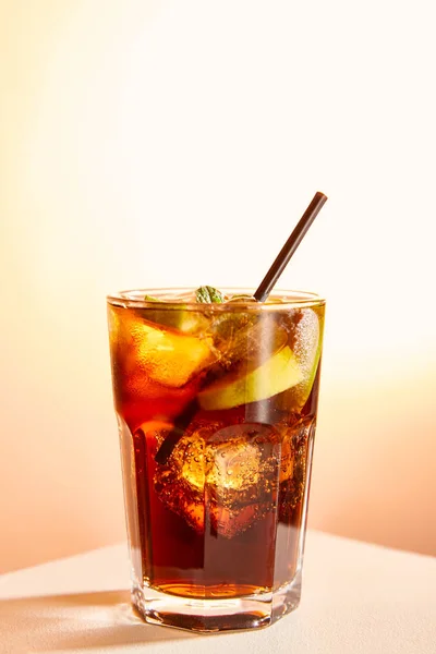 Cocktail cuba libre in glass with straw on beige background — Stock Photo