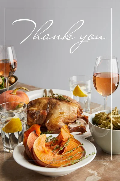 Sliced baked pumpkin near grilled turkey and glasses with rose wine on stone table isolated on grey with thank you illustration — Stock Photo