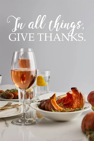 Glasses with rose wine, baked pumpkin and carrots served on white marble table isolated on grey with in all things give thanks illustration — Stock Photo
