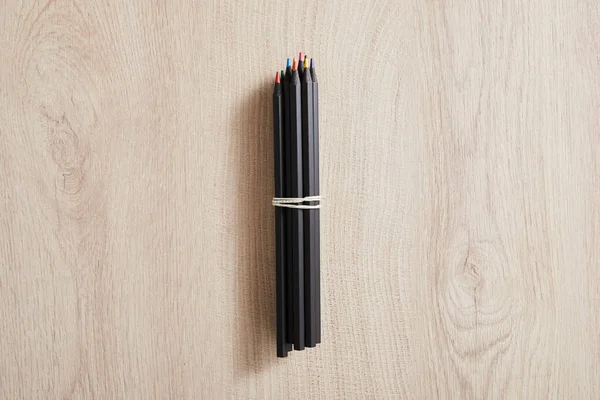 Vista dall'alto di matite di colore nero su superficie beige in legno — Foto stock