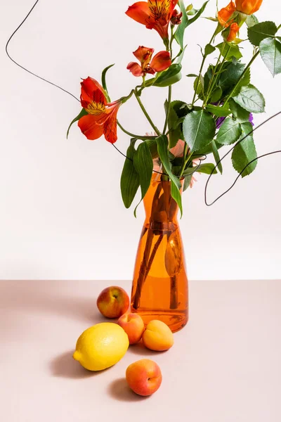 Florale Komposition mit Rosen und roten Alstroemeria in Drähten in orangefarbenen Vase in der Nähe von Zitrone und Aprikosen isoliert auf weiß — Stockfoto