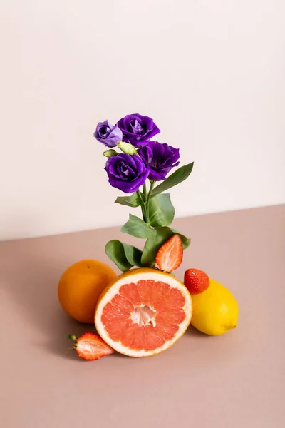 Floral and fruit composition with purple eustoma and summer fruits isolated on beige — Stock Photo