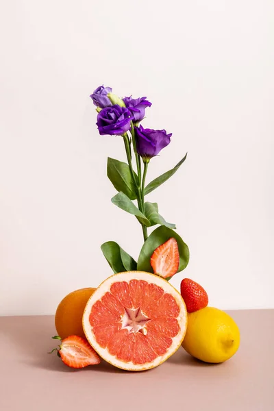 Floral and fruit composition with purple eustoma and summer fruits isolated on beige — Stock Photo