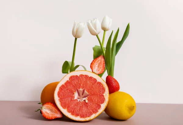 Floral and fruit composition with tulips and summer fruits isolated on beige — Stock Photo